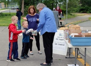 Arts Festival Foundation Board member Diane Cutts distributes grab-and-go art supply packets at Maple Leaf Elementary School.